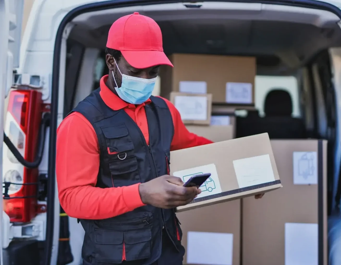 Delivery worker checking phone near van